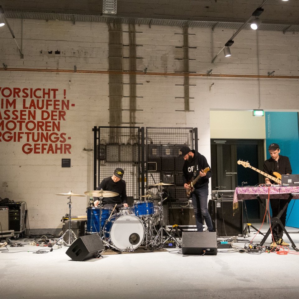 Vier Rock-Musiker mit ihren Instrumenten bei ihrem Auftritt im Infozentrum des Denkorts.