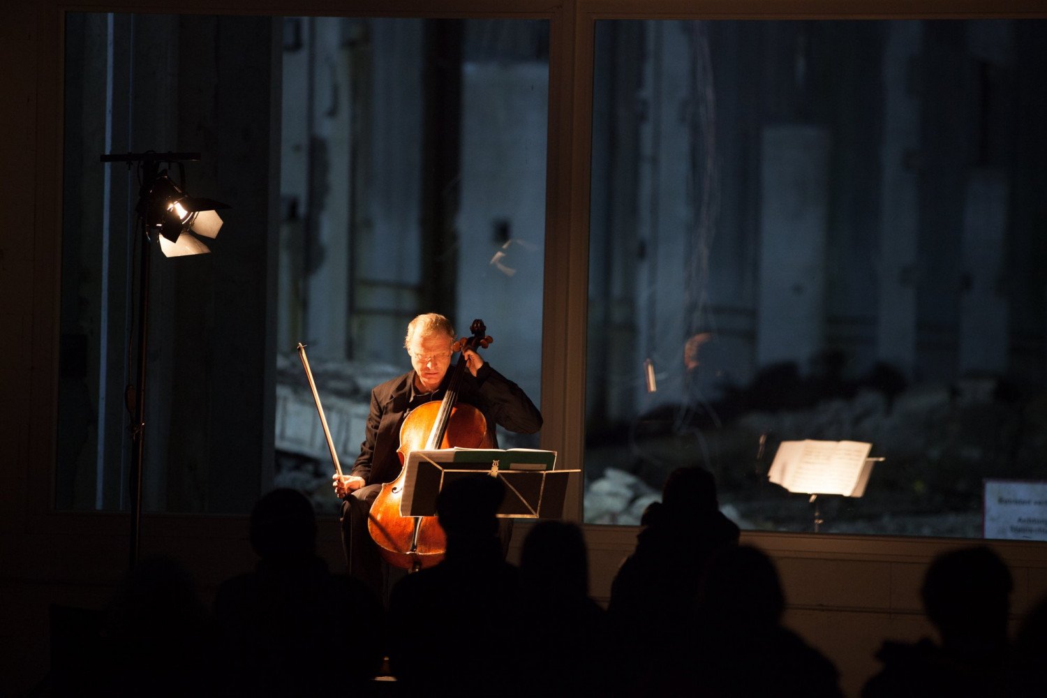 Ein Musiker mit einem Cello vor dem Ruinenteil des Bunkers.  