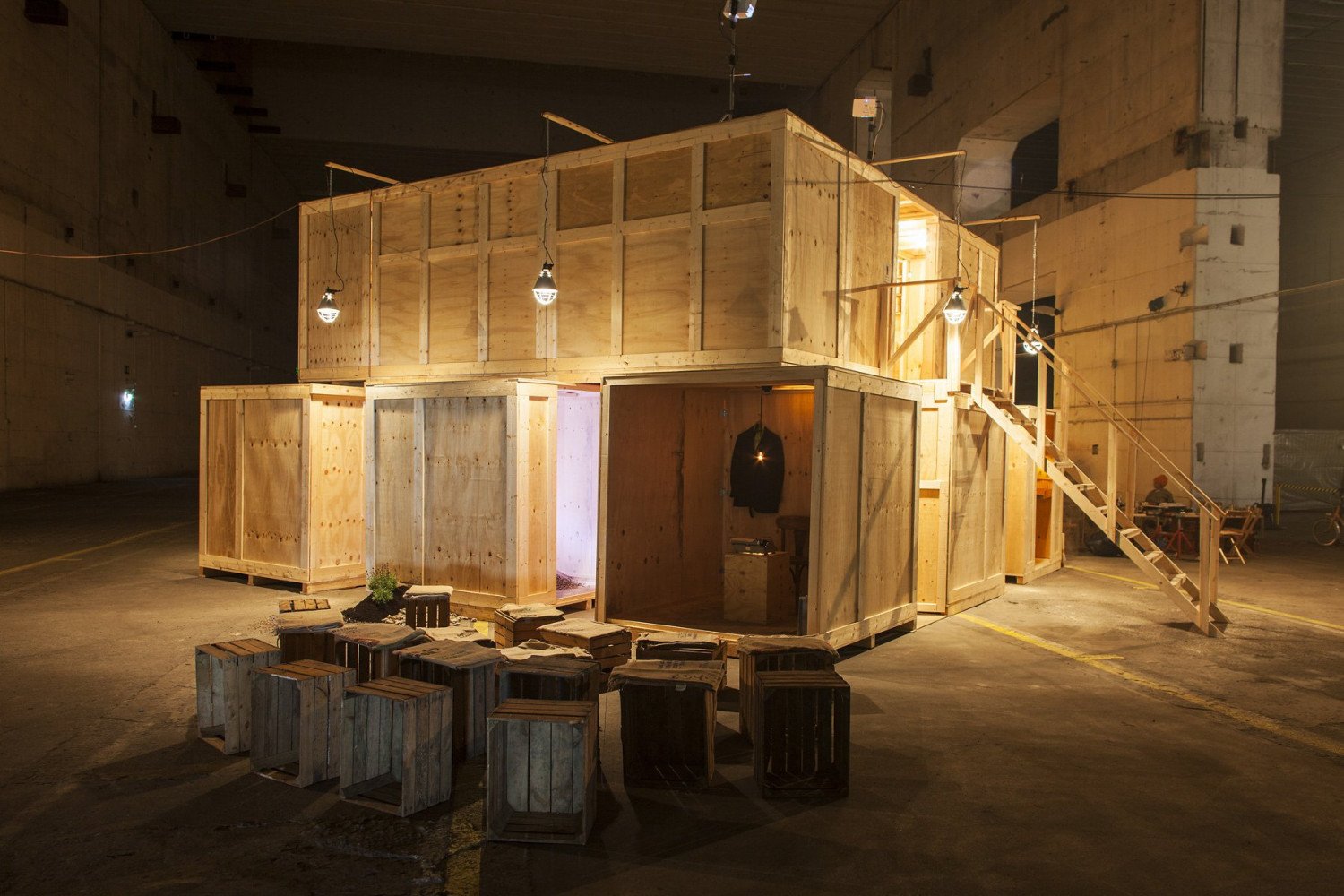 Eine große Holzbox im Bunkerinnenraum, davor leere Sitzkisten. 