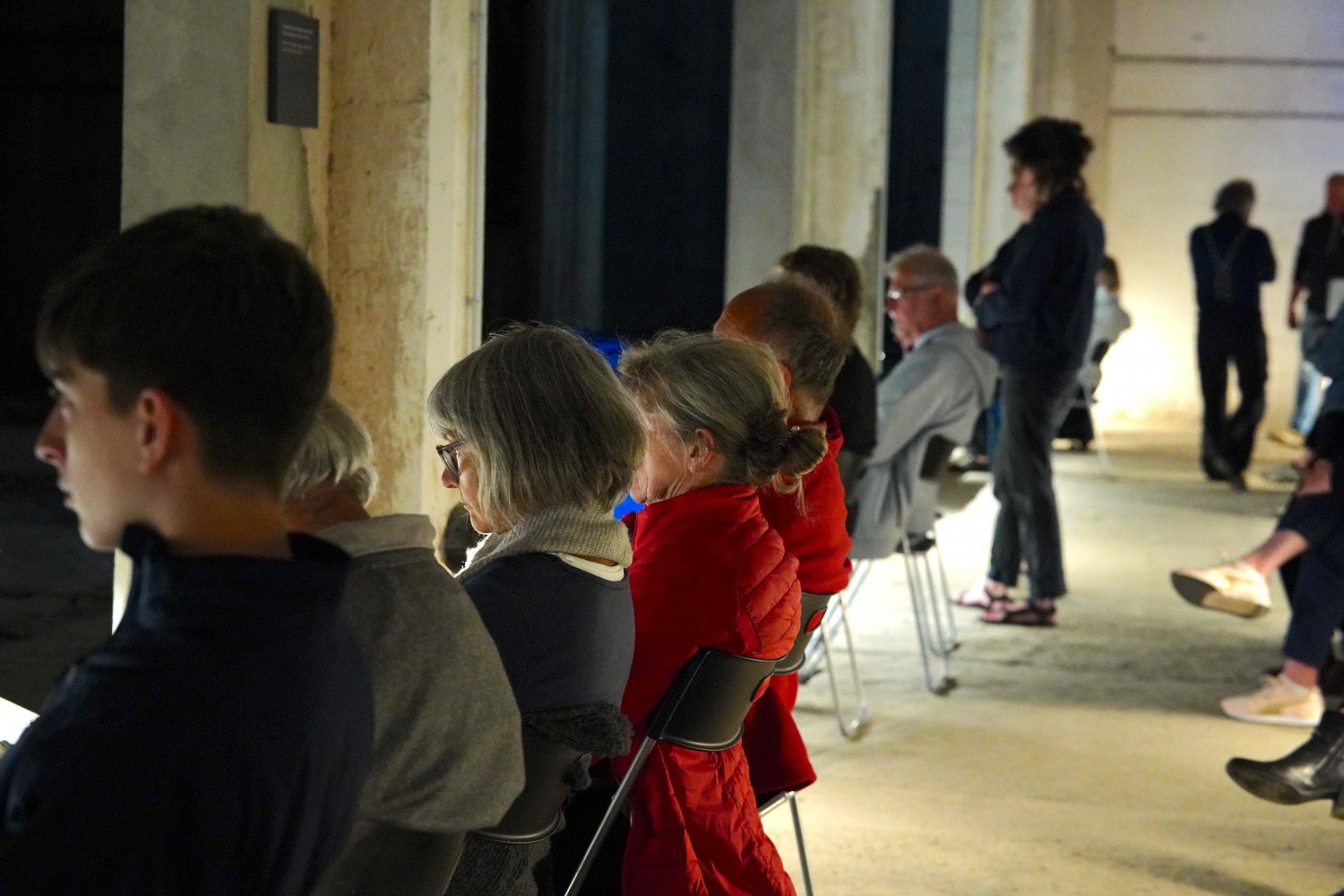 Menschen sitzen auf Stühlen im Tunnel zum Ruinenteil des Bunkers "Valentin" 