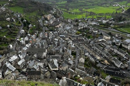 Stadtansicht von oben. Es sind Hausdächer zu erkennen. In Hintergrund sind Berge. 